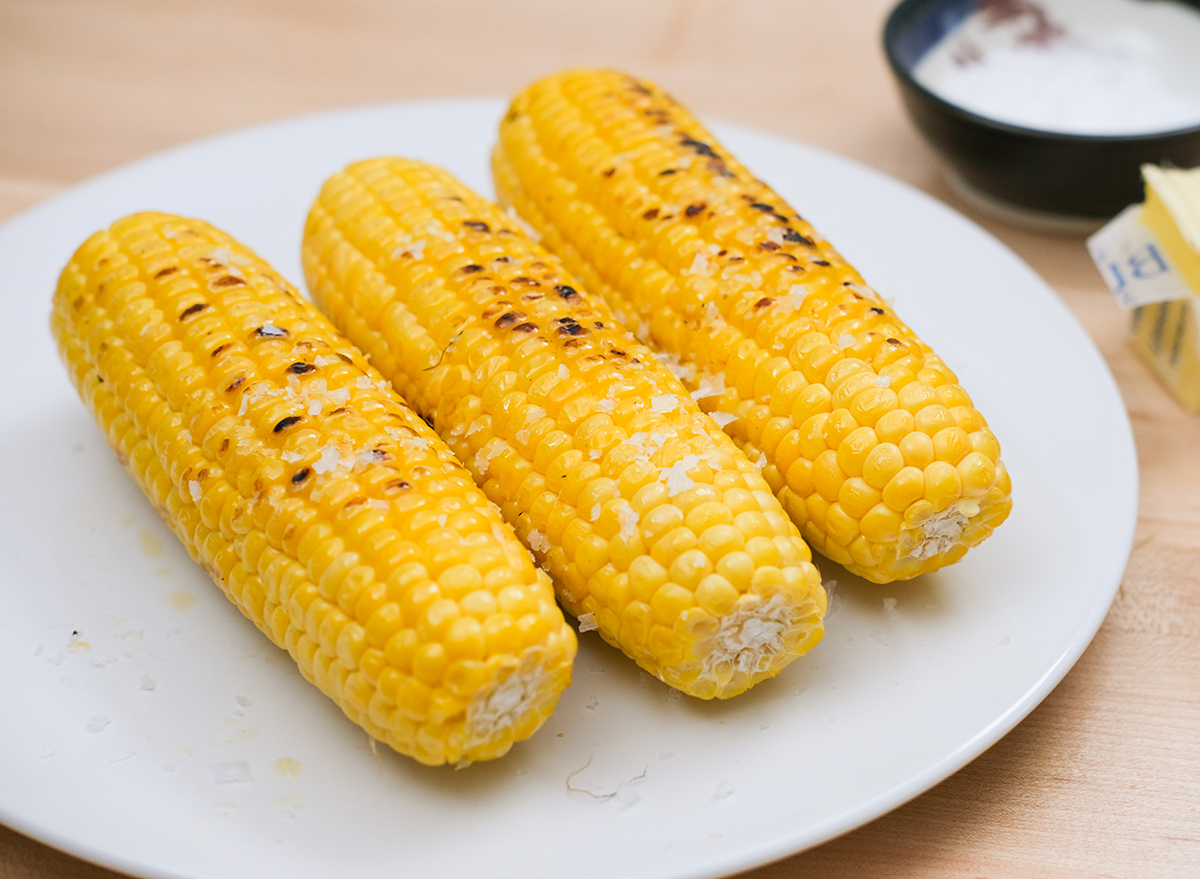 cooked corn on the cob with butter and salt on a plate
