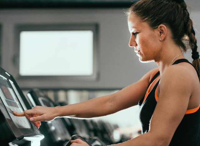 woman at gym raising treadmill incline