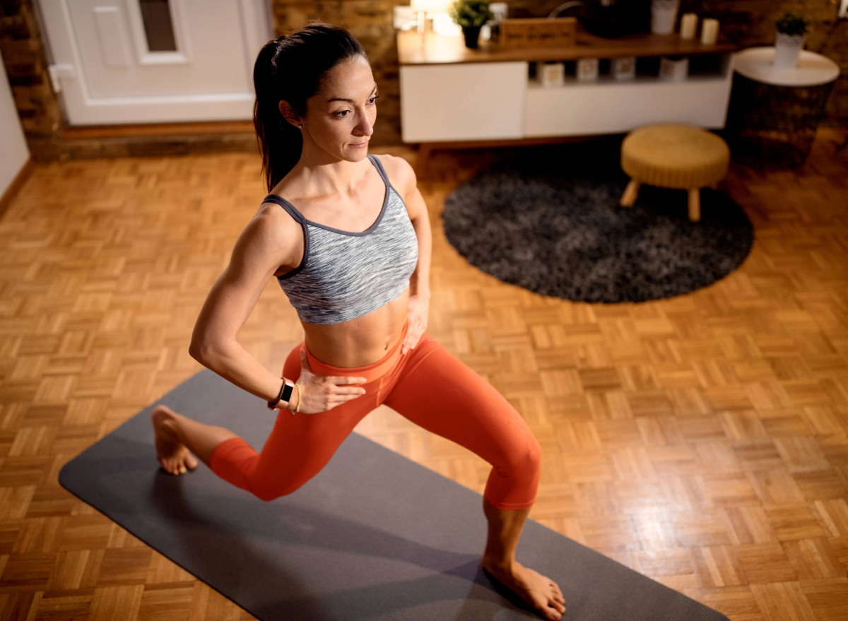 woman doing lunges on yoga mat in living room, concept of the best at-home bodyweight workouts for women to lose weight